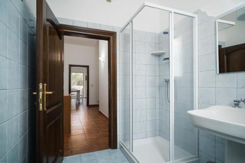 a bathroom with a glass shower door and a sink at Casa Picchereddu in Orosei
