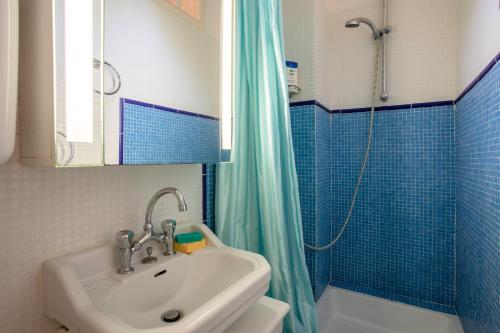 a bathroom with a sink and a shower with blue tiles at Studio Le Val de Pons Ramatuelle in Ramatuelle