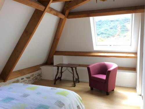a bedroom with a bed and a chair and a window at La Maison Leontine in Cahus