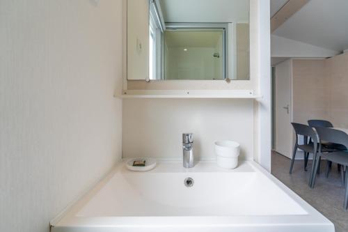a bathroom with a white sink and a mirror at Mobilhomelaco34 in Vendres