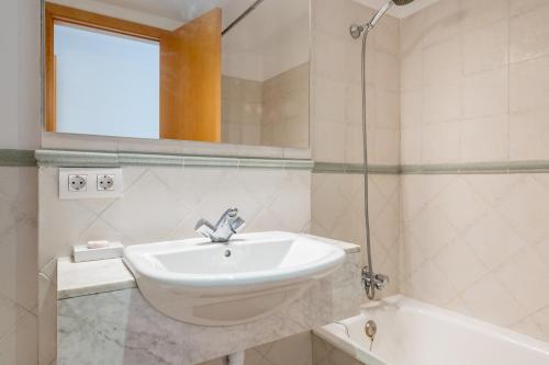 a white bathroom with a sink and a bath tub at Talaia 1a in Port de Pollensa