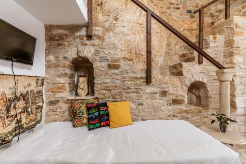 a bedroom with a stone wall with a bed with pillows at Vrahos Tinos in Panormos