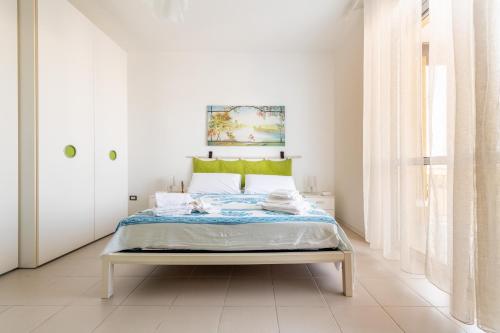 a white bedroom with a bed with a green headboard at Dimora lungomare terra d'otranto in Otranto