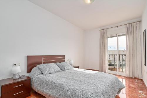 a white bedroom with a bed and a window at Casa Axarquia in Vélez-Málaga