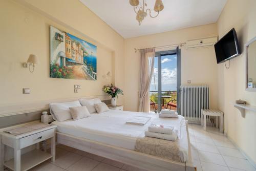 a bedroom with a large white bed and a tv at Nontas Home 22 in Kalamitsi