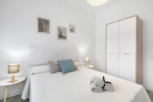 a white bedroom with a white bed and a mirror at El Ramonal Home in Candelaria