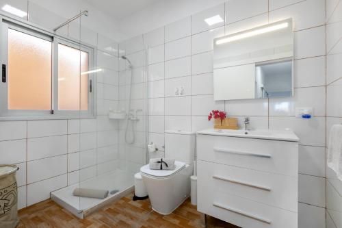 a white bathroom with a toilet and a sink at El Ramonal Home in Candelaria