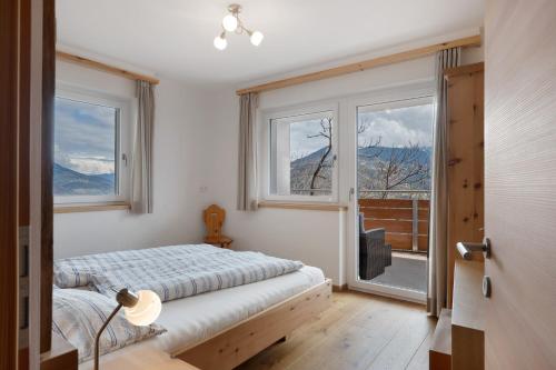 a bedroom with a bed and a large window at Haus Pferscher in Barbiano