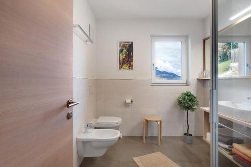 a bathroom with a toilet and a sink and a window at Haus Pferscher in Barbiano