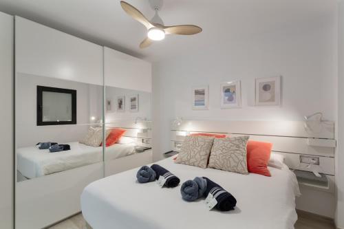 a white bedroom with two beds and a mirror at Lupama Suite in Arguineguín