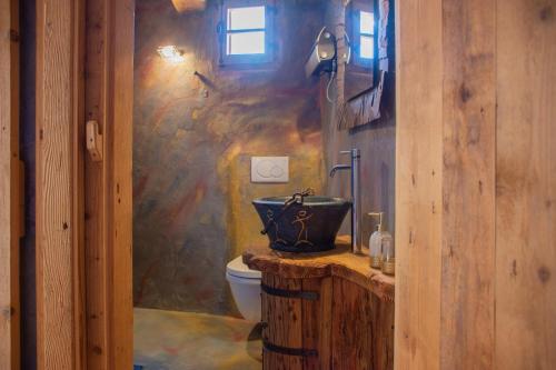 a bathroom with a toilet and a stone wall at Chalet Atmosfera Res Albert in San Guglielmo