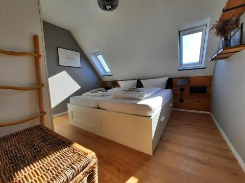a small bedroom with a bed and two windows at Ferienwohnung Möwennest by Deju in Norderney