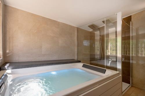 a large tub in a bathroom with a shower at Villa Trullo Ulivo with pool in Carovigno