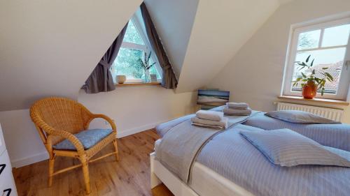 a attic bedroom with two beds and a chair at Löningen - Ferienwohnung Hasestraße in Löningen