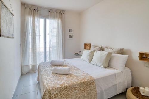 a white bedroom with a large bed with two towels on it at Apartamento en 1 línea mar in Sant Antoni de Calonge