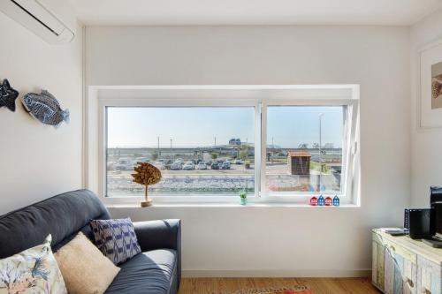 a living room with a couch and a large window at Apartamento T1 - Salina Ria in Aveiro