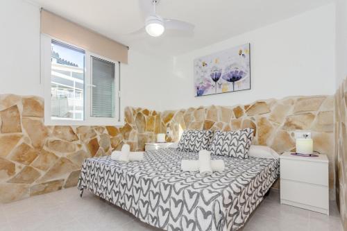 a bedroom with a bed and a stone wall at Cala en Forcat in Menorca