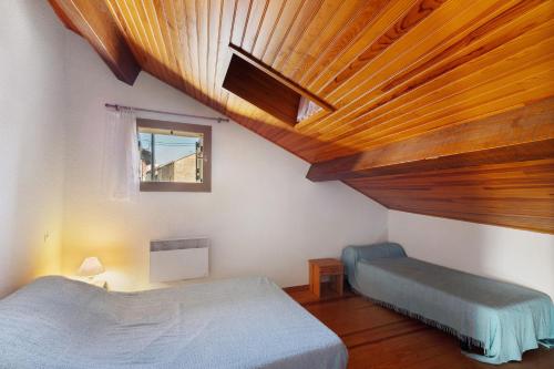a bedroom with two beds and a wooden ceiling at Maison de village Le Galbe in La Llagonne