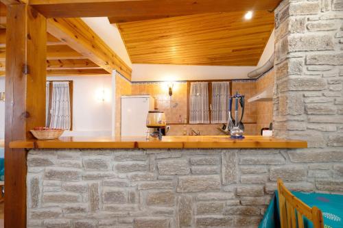 a kitchen with a stone wall and wooden ceiling at Maison de village Le Galbe in La Llagonne