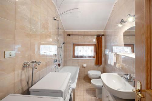 a bathroom with a sink and a toilet and a tub at Ciasa Giorgina a Pozza di Fassa in Pozza di Fassa