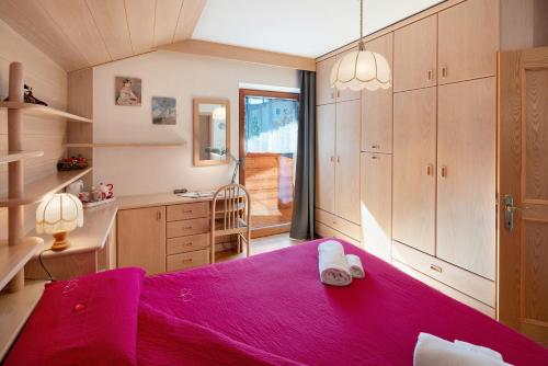 a bedroom with a bed with a pink blanket at Ciasa Giorgina a Pozza di Fassa in Pozza di Fassa