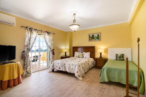 a bedroom with a bed and a tv and a window at Casa do Sobreiro in Quelfes