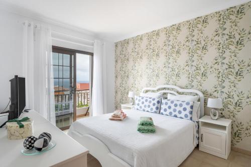 a bedroom with a white bed and a tv at Casa ino in Punta del Hidalgo