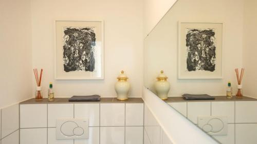 a white room with two framed pictures and vases at Ferienwohnung Jung und Lind in Bretten