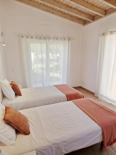 two beds in a white room with a window at Paraiso da Serva - Flor do Rosto 2 in Odemira