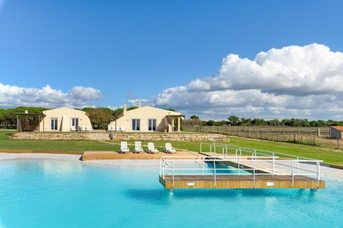a pool of water with chairs and a house at Paraiso da Serva - Flor do Rosto 2 in Odemira