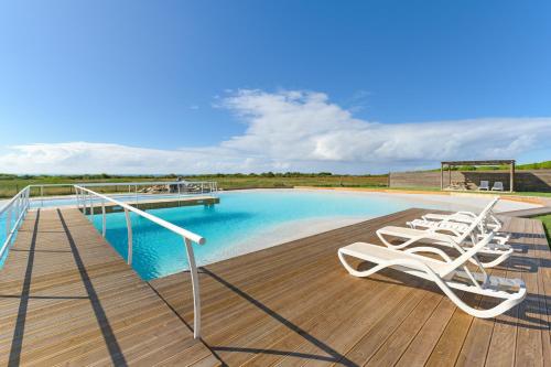 a deck with lounge chairs next to a swimming pool at Paraiso da Serva - Flor do Rosto 2 in Odemira
