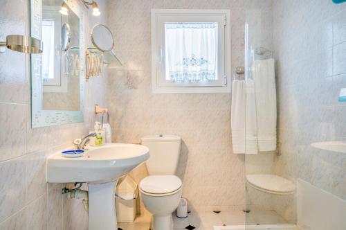 a white bathroom with a toilet and a sink at Villas Vanessa & Ruth in Cala en Porter