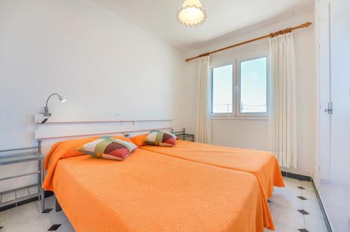 an orange bed in a white room with a window at Villas Vanessa & Ruth in Cala en Porter