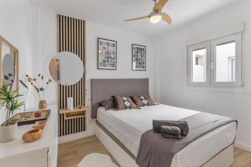 a white bedroom with a bed and a mirror at Casa con terraza cerca del mar in Telde