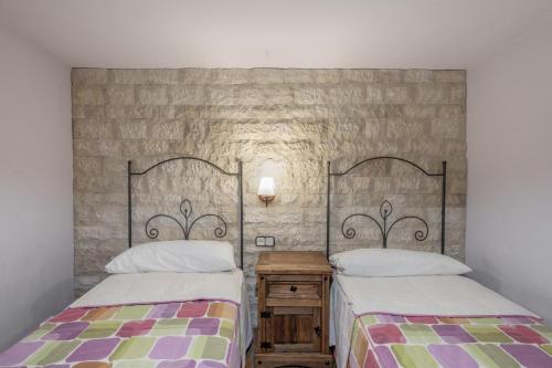 a bedroom with two beds and a stone wall at Cuatro Torres in Campillo