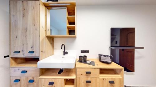 a kitchen with a sink and wooden cabinets at Apart Hennewinkl in Oetz