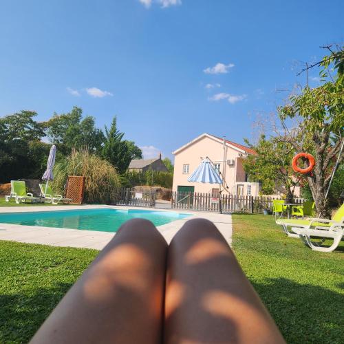a person laying on the grass in front of a swimming pool at Solar Rubina - Piscina Água Salgada in Belmonte