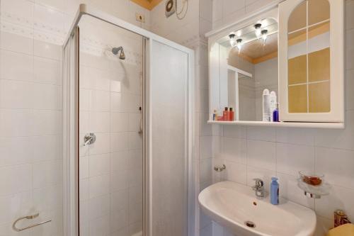 a white bathroom with a shower and a sink at Brezza del lago in Desenzano del Garda