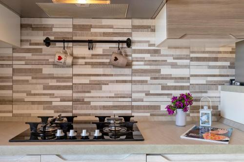 a kitchen with a stove and a wall with tiles at Villetta I Pitosfori in Palmadula
