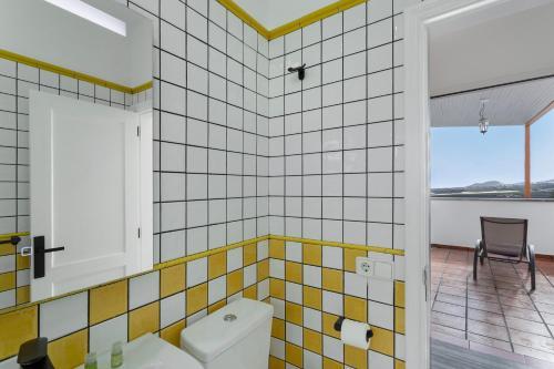 a bathroom with a toilet and a table and a chair at Los Adejo vacacional in Moya