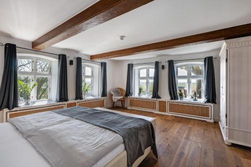 a bedroom with a large bed and windows at Knutzenswarft - Deichgraf in Westerhever