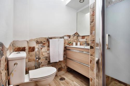 a bathroom with a white toilet and a stone wall at El Lagar in Los Silos