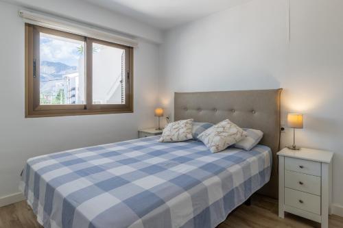 a bedroom with a blue and white bed and a window at Top first line apartment Altea in Altea