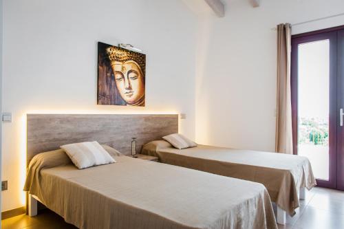 two beds in a room with a painting on the wall at Can Vadell in Calonge