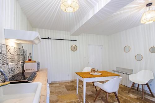 a kitchen with a table and white chairs and a table at Appartement La Pierre in Saint-Médard-de-Mussidan
