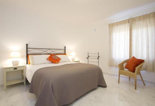 a white bedroom with a bed and a chair at Casa Mcelroy in Tías