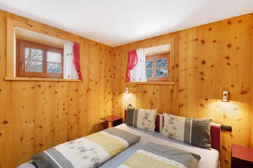 two beds in a room with wooden walls at Tea da Anna e Luigi in Livigno