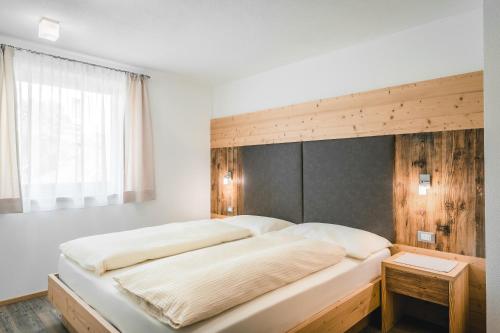 a bedroom with a large bed with a wooden headboard at Chalet La Flüta Primula in La Valle
