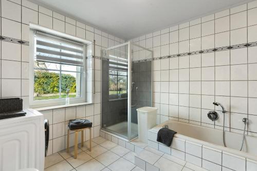 a white tiled bathroom with a tub and a window at Ferienwohnung Dora in Medebach