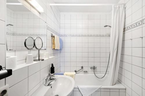 a white bathroom with a tub and a sink at Fewo Brünnstein - Nr 44 Pool, Sauna in Oberaudorf